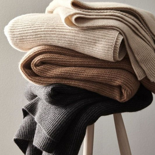 Cosy knitwears and stylish sweaters neatly folded on a chair