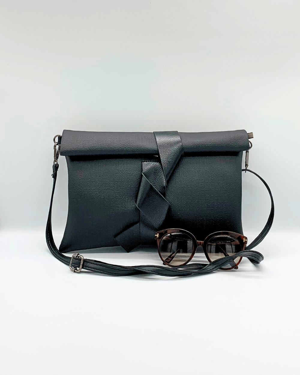 A fun cross body bag. H 30 cm x L 2 cm x W 21 cm - Faux leather; fully-lined interior - Ribbon front closure - Polished silver-toned hardware - Single detachable handle