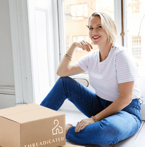 Smiling blonde woman wearing a t-shirt and jeans with a Threadicated parcel